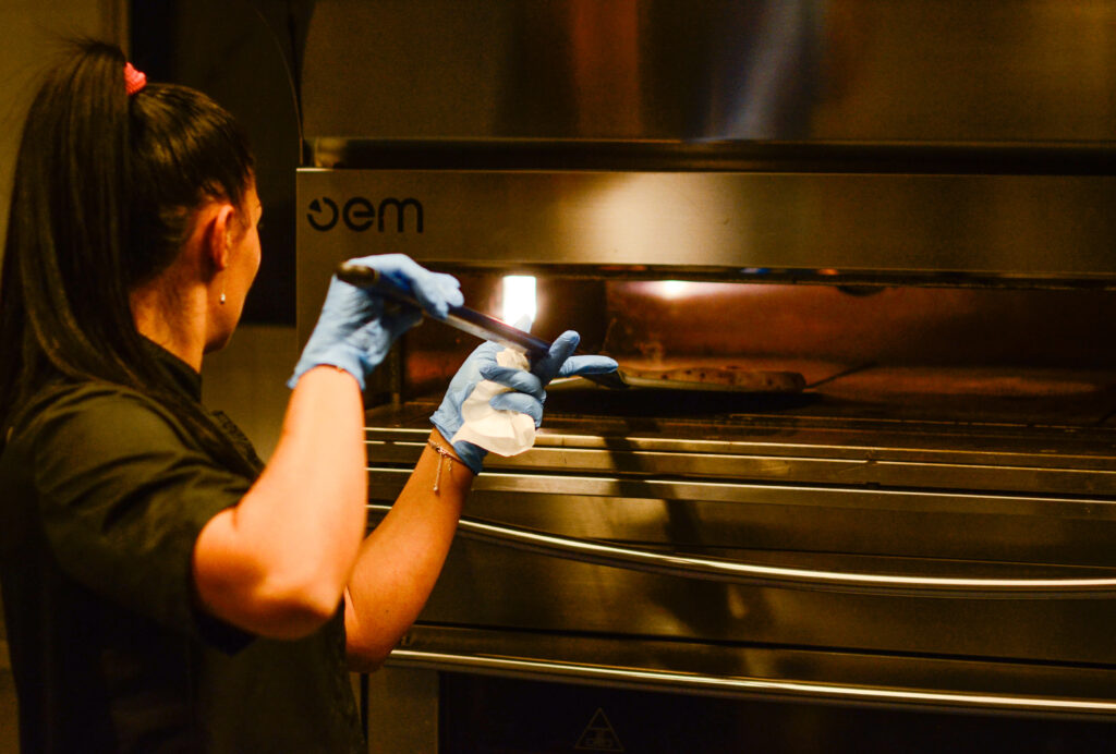 pizzaiolo che sta tirando fuori la pizza dal forno del laboratorio a vista di Salamensa